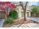 Inviting exterior showcasing a two-car garage, arched entry, and colorful landscaping at 10235 Headrick Dr, Las Vegas, NV 89166