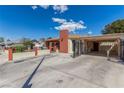 Single-story home showcasing a large driveway, carport, and brick chimney under a bright, sunny sky at 2254 Florence Ave, Las Vegas, NV 89119