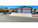 This exterior shows a home with a spacious three car garage and beautiful front yard at 7461 Tahoe Basin Dr, Las Vegas, NV 89129