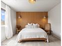 Cozy bedroom showcasing a wooden accent wall, pendant lighting, and minimalist decor at 7476 Opal Star St, North Las Vegas, NV 89084