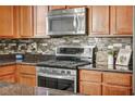 This kitchen features stainless steel appliances, dark countertops, and natural wood cabinets at 1152 Pine Cove Ct, Henderson, NV 89011