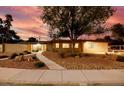 Charming single-story home with desert landscaping and a walkway leading to a bright yellow front door during dusk at 3597 Cochise Ln, Las Vegas, NV 89169