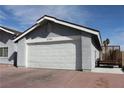 Attached two-car garage with white door and a gray exterior, complemented by a well-kept driveway at 7170 Mountain Moss Dr, Las Vegas, NV 89147