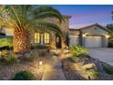 Inviting front entrance with a stone path and a stone facade, enhanced by lush landscaping and evening lighting at 7181 Barton Creek Ct, Las Vegas, NV 89113
