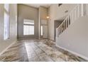 Spacious living room with high ceilings, tile flooring, a staircase, and large windows filling the space with light at 8944 Campanella St, Las Vegas, NV 89123