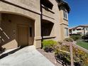 Exterior view of a condo with a beige door, walkway, and neat landscaping at 8985 S Durango Dr # 1010, Las Vegas, NV 89113