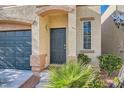 Close up view of the front door and adjacent garage, with front yard plants at 9066 Hilverson Ave, Las Vegas, NV 89148