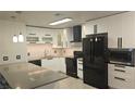 Modern kitchen features black appliances, white cabinetry, gray countertops, and stylish pendant lighting at 928 Rockview Dr # 102, Las Vegas, NV 89128