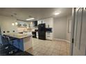 Spacious kitchen features white cabinets, black appliances, island with bar seating, and tile flooring at 928 Rockview Dr # 102, Las Vegas, NV 89128