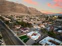 Stunning aerial view of the community with mountain backdrop, lush greenery, and city lights in the distance at 6861 E Washington Ave, Las Vegas, NV 89110