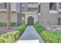 Inviting building entrance with decorative shrubs and plants leading to an arched doorway and address number at 9213 Las Manaitas Ave # 401, Las Vegas, NV 89144