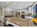 Modern kitchen with a granite countertop island, stainless appliances, and adjacent dining area for seamless entertaining at 6361 W Viking Rd, Las Vegas, NV 89103