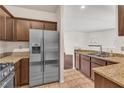 Modern kitchen with stainless steel refrigerator, granite countertops, and brown cabinetry at 2050 W Warm Springs Rd # 1822, Henderson, NV 89014