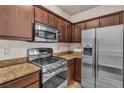 Kitchen features stainless steel appliances, including a microwave and gas range, with granite countertops and brown cabinets at 2050 W Warm Springs Rd # 1822, Henderson, NV 89014