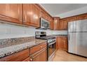 Close up of a kitchen with stainless steel appliances, wood cabinetry and granite countertops at 2612 Kindness Ct, North Las Vegas, NV 89031