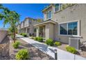 View of the townhome exterior featuring a paved walkway, stone landscaping, and a quaint covered entrance at 5730 Sky Pointe Dr # 104, Las Vegas, NV 89130