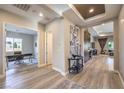 Open-concept home foyer featuring stylish wood-look flooring, designer lighting, and views into office and living areas at 8445 S Tenaya Way, Las Vegas, NV 89113