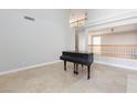 Neutral living room boasts an open floor plan, tile flooring, neutral paint and a grand piano at 8617 Copper Ridge Ave, Las Vegas, NV 89129