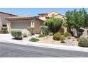 Frontal view of tan two-story home with mature trees and shrubs at 932 Tafalla Ct, Las Vegas, NV 89138