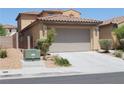 Frontal view of tan two-story home showcasing a tile roof and a two-car garage at 932 Tafalla Ct, Las Vegas, NV 89138