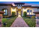 Front exterior of a luxurious home with stone accents, a paver walkway, professional landscaping and accent lighting at 10 Olympia Outlook Dr, Las Vegas, NV 89141