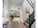 Bright foyer featuring wood flooring, a staircase with black railing, and views of the living area at 10305 Turia Gardens Rd, Las Vegas, NV 89135