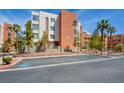 Exterior of the condo building shows the architectural style with palm trees and parking spots out front at 23 E Agate Ave # 207, Las Vegas, NV 89123