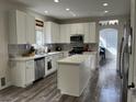 Modern kitchen with white cabinets, stainless steel appliances, a center island, and wood-look floors at 3749 Climbing Rose St, Las Vegas, NV 89147