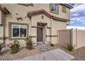 Exterior of a two-story townhome featuring a brown front door, beige stucco, and landscaped walkway at 7915 Pandora Sky St # 402, Las Vegas, NV 89084