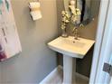 Clean and modern powder room featuring a pedestal sink, round mirror, and decorative accents at 116 Antler Square Ln, Henderson, NV 89011