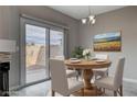 Cozy dining room showcasing a round wooden table, modern chandelier, and sliding door to patio at 1660 Cloister Ave, Henderson, NV 89014