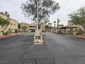 View of the entrance to a condominium complex, featuring a security gate, mature landscaping, and well-maintained grounds at 1858 N Decatur Blvd # 204, Las Vegas, NV 89108