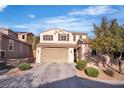 Two-story house featuring desert landscaping, a three-car garage, and shuttered windows under a vibrant blue sky at 235 Desert Arroyo Ct, Henderson, NV 89012