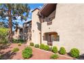 Exterior shot of a charming condo with a tile roof, red rock landscaping, and lush green shrubbery at 4097 Nook Way # A, Las Vegas, NV 89103