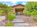 Quaint front porch with seating, complemented by lush landscaping and stone accents at 689 Silver Pearl St, Henderson, NV 89002