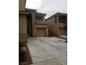 Two-story tan home with a concrete driveway, shutters, and an attached garage at 7073 Seabirds Pl, North Las Vegas, NV 89084
