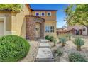 Well-maintained two-story home with manicured landscaping, a stone archway, and a concrete walkway to the front door at 9413 Artesian Oak Ct, Las Vegas, NV 89149
