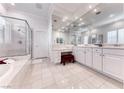 Bright bathroom featuring double sinks, large mirrors, a walk-in shower, and a soaking tub at 14 Hunt Valley Trl, Henderson, NV 89052