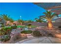 Lush backyard with a putting green, desert landscaping, and a covered patio area at 2248 Carrizo Way, Henderson, NV 89052
