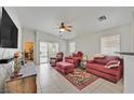 Bright living room with a ceiling fan, tile flooring, and sliding door to the backyard at 4920 River Splash Ave, Las Vegas, NV 89131