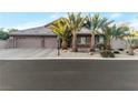 Charming home exterior featuring a three-car garage and lush palm tree landscaping at 6012 Chessington Ave, Las Vegas, NV 89131
