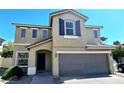 Two-story tan home with a two-car garage, covered entry, and neatly trimmed landscaping at 6348 Blue Twilight Ct, Las Vegas, NV 89108