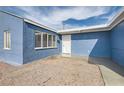 Exterior of a blue single story house with a white door and a gravel yard at 143 Constitution Ave, Henderson, NV 89015