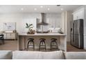Modern kitchen featuring white cabinets, stainless steel appliances, island with bar seating, and stylish backsplash at 1624 Preston Park Dr, Henderson, NV 89052