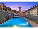 Beautiful backyard pool and spa with a rock waterfall feature and lush landscaping, creating a private oasis at 18 Via Tiberina, Henderson, NV 89011