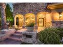 Elegant entrance to a stone house with an arched doorway and decorative wrought iron door at 2845 Red Arrow Dr, Las Vegas, NV 89135