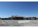Wide shot of desert home featuring a tile roof, gravel landscaping, and a large RV parked on the side at 3020 Peggy Ave, Pahrump, NV 89048