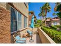 Relaxing patio with comfortable seating, an umbrella, and views of lush landscaping and palm trees at 3840 Belle Glade St # 104, Las Vegas, NV 89129