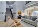 View of the bright living room with a staircase, piano, comfortable sofa, and two-story ceilings at 7256 Bugler Swan Way, North Las Vegas, NV 89084
