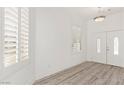 Welcoming entryway with wood-look floors, white walls, plantation shutters, and a double front door at 9228 Whitekirk Pl, Las Vegas, NV 89145